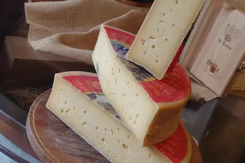 Fette di formaggio stagionato, con buchi, su un tagliere. Attenzione, la scamorza fa ingrassare!