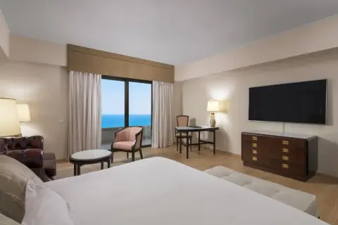 Elegancki pokój z widokiem na morze, idealny na pobyt w Rodos Palace. Wygodne łóżko, stylowe meble i balkon z zapierającym dech w piersiach widokiem.