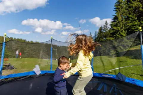 Dzieci skaczą na trampolinie w ziemi. Dowiedz się, jak zrobić taką trampolinę, by zapewnić im mnóstwo radości!