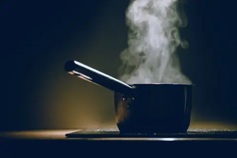 Para unos fideos perfectos, el parowanie jest kluczowe. Garnek z parującą wodą na ciemnym tle.