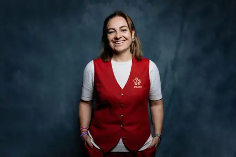 Uśmiechnięta kobieta w kamizelce z godłem Polski, część sztabu szkoleniowego reprezentacji Polski.