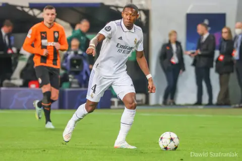 Piłkarz Realu Madryt w białej koszulce z numerem 4, David Alaba, prowadzi piłkę. W tle widać zawodnika Szachtara Donieck w pomarańczowej koszulce. To obraz jednego z najlepszych obrońców świata.