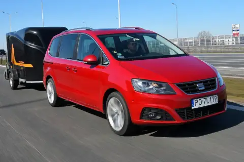 Czerwony Seat Alhambra z przyczepą na autostradzie. Zastanawiasz się, ile możesz jechać z przyczepą na autostradzie?