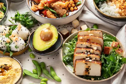 Kolorowe dania, w tym hummus, ryż, awokado i grillowane tofu, idealne do diety bogatej w błonnik przepisy.