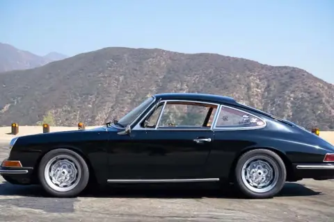 Klasyczny czarny Porsche 912 z lat 60. na tle górskich krajobrazów.