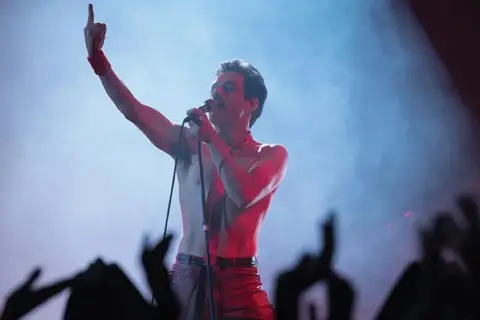 Rami Malek jako Freddie Mercury śpiewa w "Bohemian Rhapsody", porywając tłum gestem i głosem.