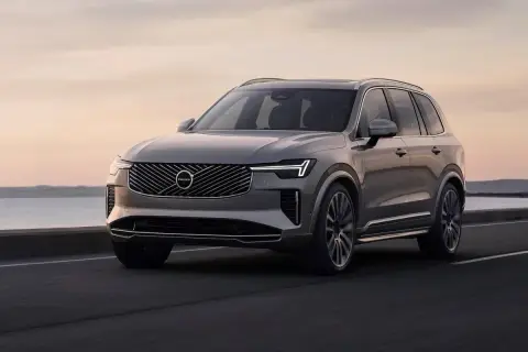 Szary Volvo XC90 jedzie po drodze nad morzem. Sprawdź aktualną volvo xc90 cena.