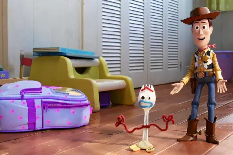 Woody i Forky, bohaterowie filmów dla całej rodziny, stoją obok fioletowego plecaka w pokoju dziecięcym.
