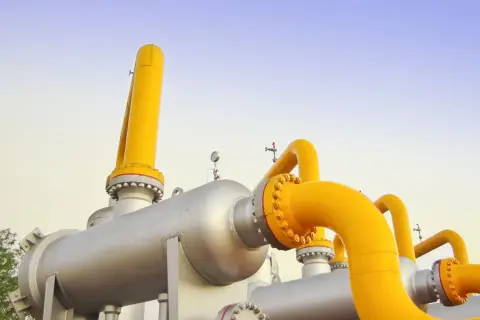 System rur i zbiorników przemysłowych, przez które przepływa gaz ziemny, na tle błękitnego nieba.