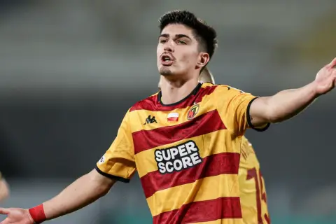 Piłkarz Korony Kielce w żółto-czerwonej koszulce z napisem "SUPER SCORE" gestykuluje podczas meczu z Jagiellonią Białystok.