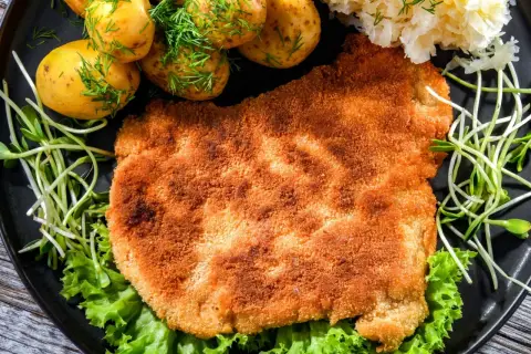 Chrupiący kotlet w panierce panko Lidl, podany z młodymi ziemniaczkami, kiszoną kapustą i kiełkami.