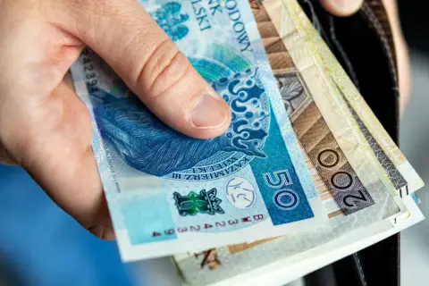 Dłoń trzyma polskie banknoty: 50 zł i 200 zł. Wkrótce trzeba będzie zapłacić czynsz.