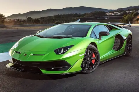 Jaskrawozielony Lamborghini Aventador SVJ na torze wyścigowym, z górami w tle.