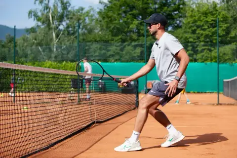 Trener pokazuje, jak dobrać rakietę tenisową, ćwicząc na korcie.