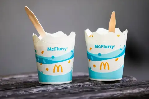 Dwa kubeczki McFlurry z drewnianymi łyżeczkami. Idealne na deser, ale warto sprawdzić mcflurry kcal przed spożyciem.