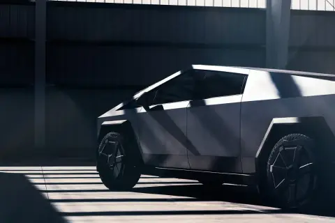 Futurystyczny Cybertruck Tesla w surowym wnętrzu, oświetlony promieniami słońca.