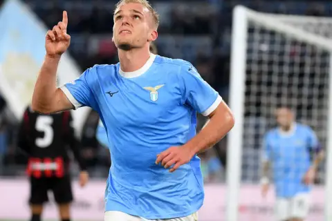 Piłkarz Lazio w błękitnej koszulce z uniesionym palcem, radośnie świętuje bramkę w meczu z A.C. Milan.