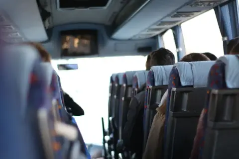 Wygodny transport gości weselnych autobusem. Widok z wnętrza pojazdu na siedzących pasażerów.