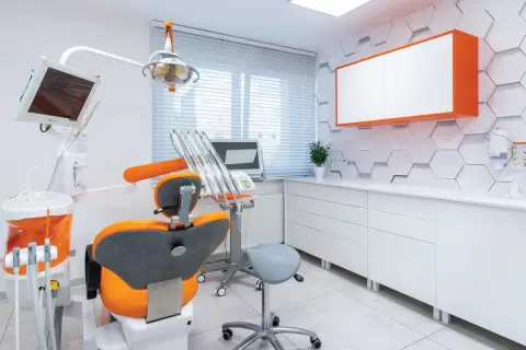 Nowoczesny gabinet stomatologiczny z fotelem, unitem i szafkami.