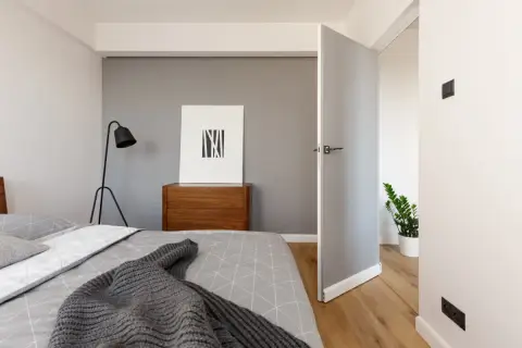 Nowoczesna sypialnia z łóżkiem, komodą i obrazem. Idealne miejsce na **najem krótkoterminowy**, oferujące komfort i styl.