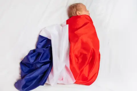 Noworodek owinięty w flagę Francji na białym tle.