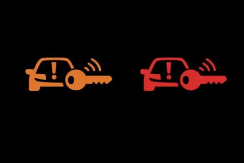 Pomarańczowa i czerwona kontrolka auto z kluczem. Sygnalizuje problem z immobilizerem lub kluczykiem.