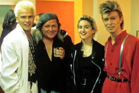 Cztery osoby: Billy Idol, reżyser, Madonna i David Bowie, pozują do zdjęcia.