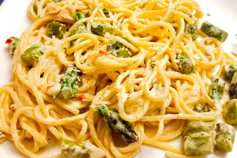 Pyszne spaghetti ze szparagami w kremowym sosie, posypane parmezanem. Idealne danie na wiosnę.