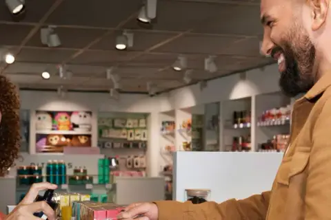 Uśmiechnięta sprzedawczyni w stena line sklepie bezcłowym prezentuje klientowi perfumy.