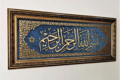 Złota kaligrafia "Bismillah" na granatowym tle, w bogatej, zdobionej ramie.