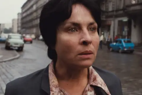 Kobieta samotna film. Zamyślona twarz kobiety na tle ulicy z samochodami i budynkami.