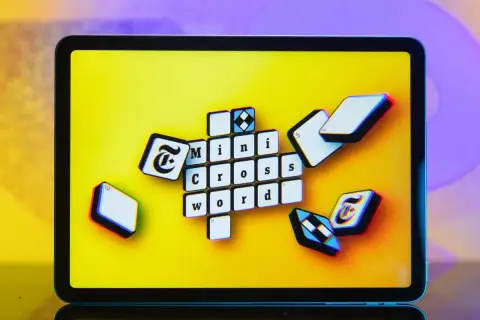 Pomoc krzyżówkowicza z przymrużeniem oka: litery "Mini Cross Word" na ekranie tabletu, jakby ktoś szukał podpowiedzi.