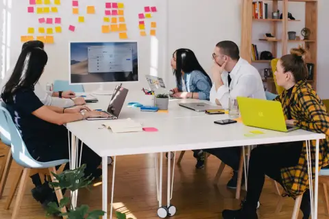 Zespół pracuje nad projektem, a tablica z notatkami sugeruje proces onboardingu.