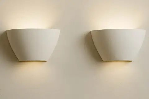 Dos elegantes flexos de pared blancos emiten una luz cálida y difusa, creando un ambiente acogedor en la estancia.