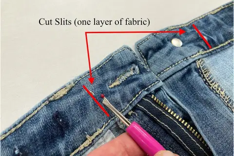Demonstration of how to take in jeans at the waist by cutting slits in the fabric.