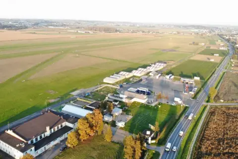 Lotnisko z hangarem i pasem startowym. W oddali widać pola i zabudowania. To miejsce, gdzie każdy wielki zwycięzca może wylądować.