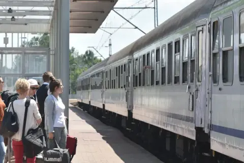 Ludzie czekają na pociąg PKP. Zastanawiają się, ile wynosi zniżka uczniowska PKP, by podróżować taniej.