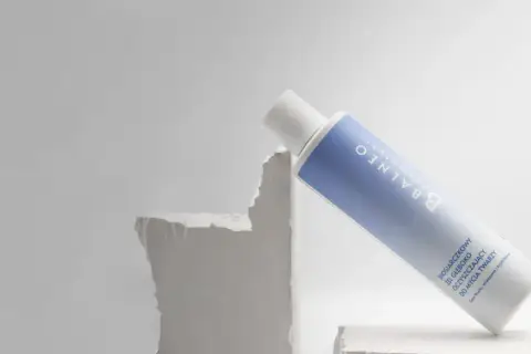 Biała butelka z niebieską etykietą, zawierająca żel do mycia twarzy. Czy to rozwiązanie na nadmiar sebum?