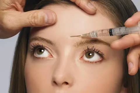 Nahaufnahme einer Frau, der Botox in die Stirn injiziert wird. Mögliche botox spätfolgen im Blick.