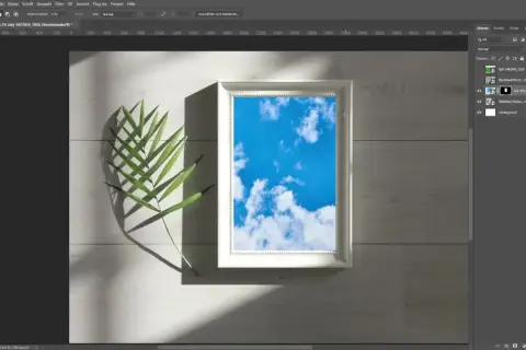 Ein Photoshop-Mockup mit einem weißen Rahmen, der einen blauen Himmel zeigt, daneben ein grünes Blatt.