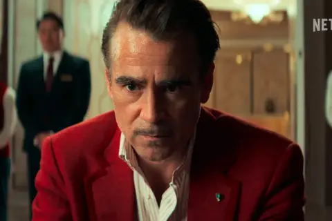 Colin Farrell in un film Netflix, con un'espressione intensa, indossa una giacca rossa.