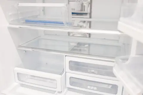 Puste półki i szuflady lodówki, gotowe do rozmrożenia i ponownego zapełnienia.