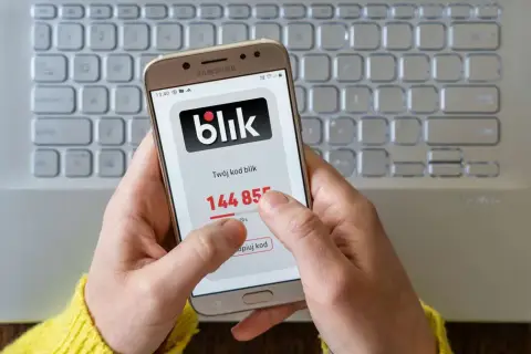 Dłoń trzyma smartfon z kodem blik. Szybki zwrot pieniędzy jest na wyciągnięcie ręki.