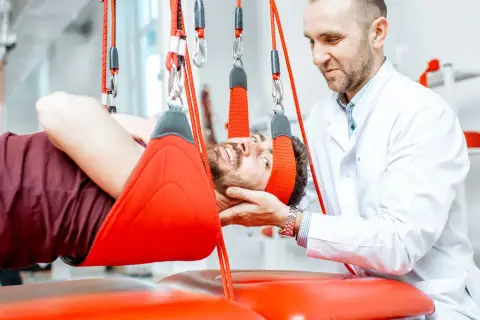 Fizjoterapeuta wspiera pacjenta podczas terapii wiszącej, która pomaga w leczeniu problemów z kręgosłupem.