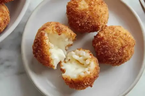 Croquettes de riz italiennes dorées et croustillantes, une bouchée révèle un cœur fondant. Parfaites pour une recette facile.