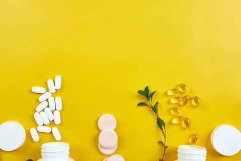 Weiße Pillen, Kapseln und Brausetabletten auf gelbem Grund. Informationen zu Chondroitin Nebenwirkungen sind wichtig, bevor man solche Präparate einnimmt.