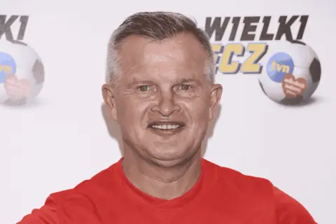 Uśmiechnięty bieleninik z TVN w czerwonej koszulce, na tle piłki nożnej z logo WOŚP.
