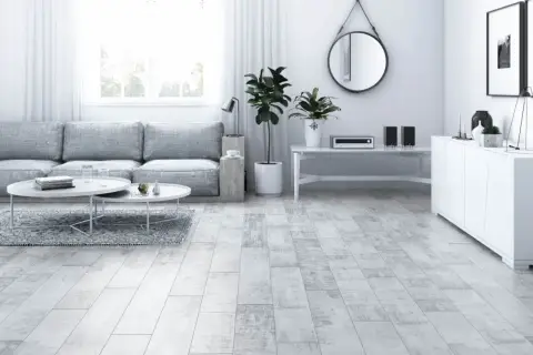 Jasny salon z szarą kanapą, białymi stolikami i podłogą imitującą drewno hikora.