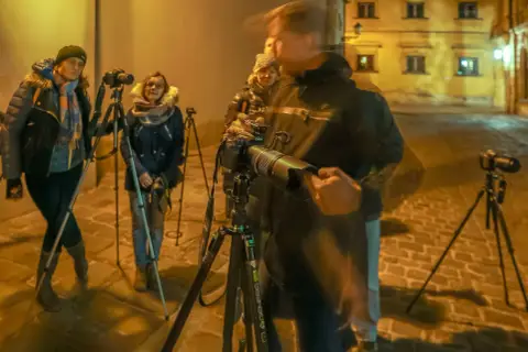 Uczestnicy kursu fotografii dla początkujących ćwiczą nocne zdjęcia na brukowanej uliczce.