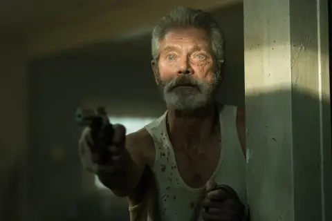 Starzec z pistoletem, w podkoszulku poplamionym krwią, wygląda groźnie. Scena z filmu "Nie oddychaj".